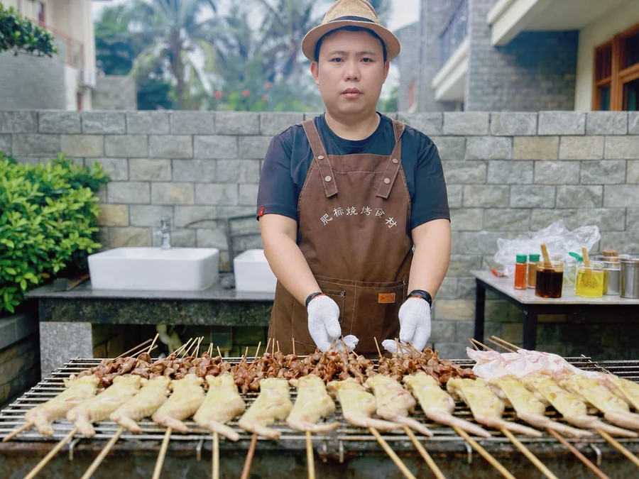 餐饮老板肥标在户外炭火前烤制上门团建烤串的真实工作现场